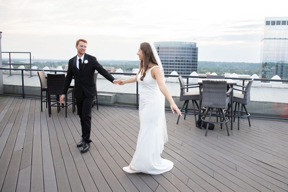 A couple dances together on a wooden deck overlooking a scenic waterfront view.