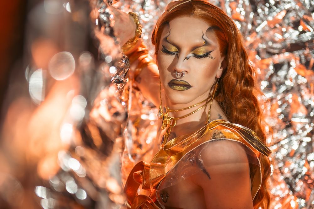 Artistic portrait with orange and silver reflective elements creating ethereal lighting effects.