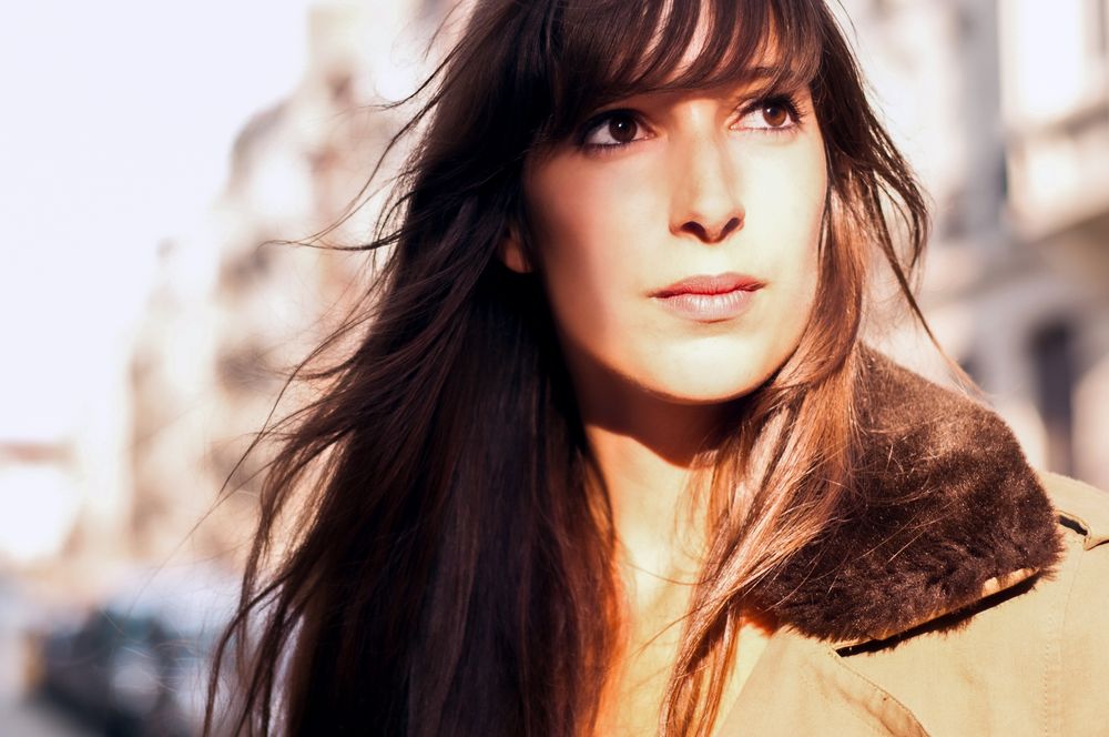 Sun-lit outdoor portrait with long hair flowing in natural light.