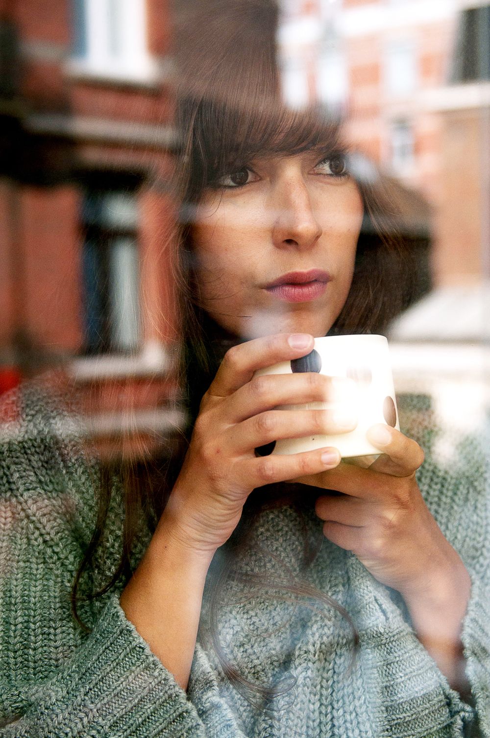 Series of images showing someone in a gray sweater sipping from a white coffee cup by a window.