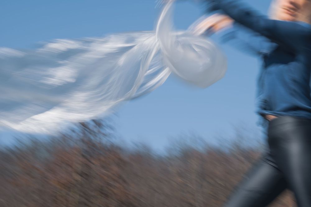 Flowing white dress fabric caught in motion against a blue sky background.