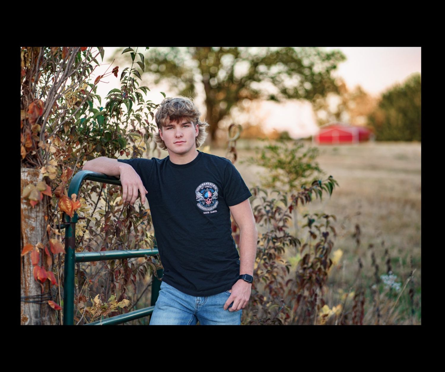 teen male leans on fence post