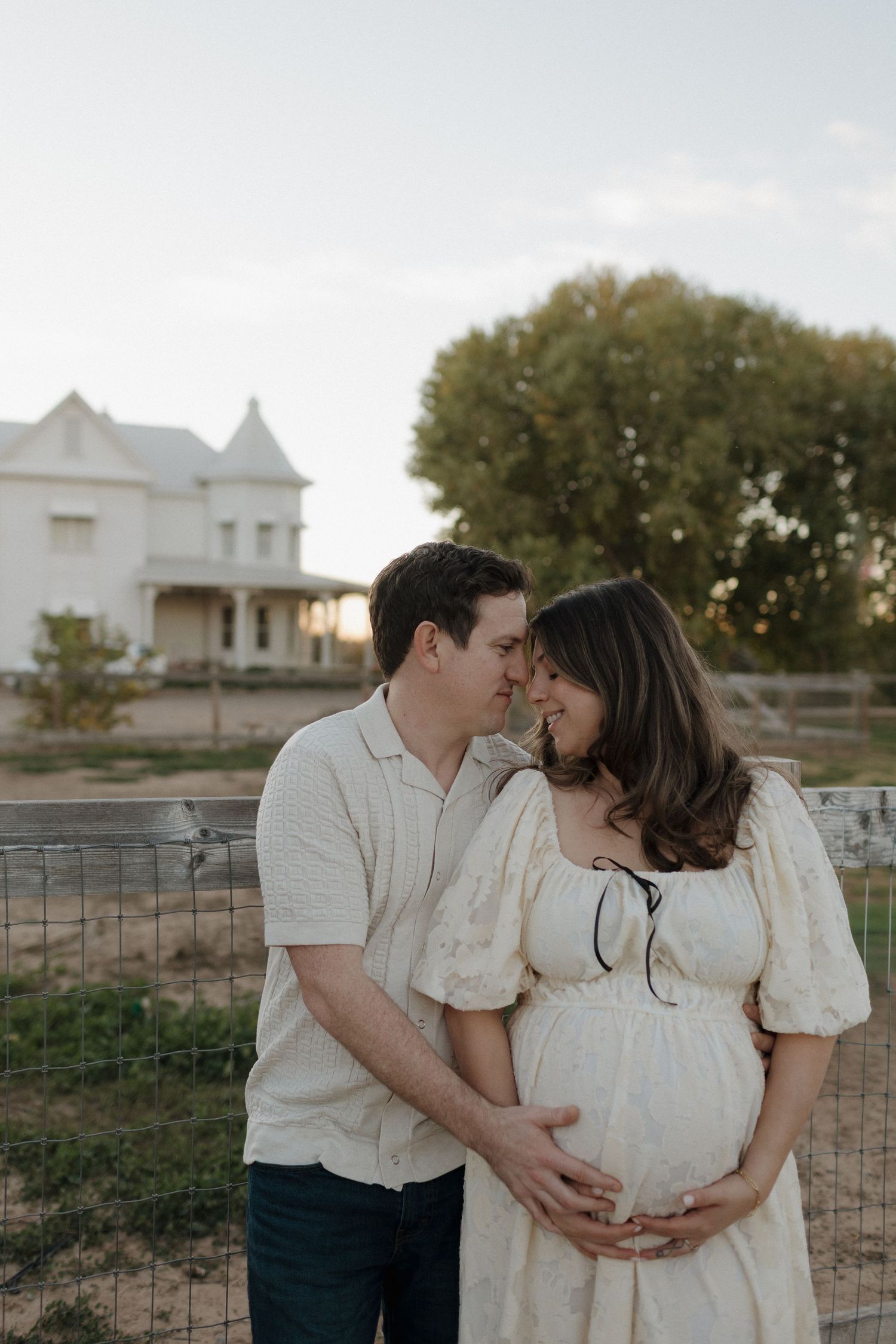Outdoor maternity announcement photo with couple holding ultrasound prints in desert setting.