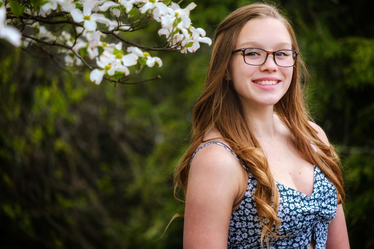Portrait in front of blooming white dogwood flowers on sunny spring day.