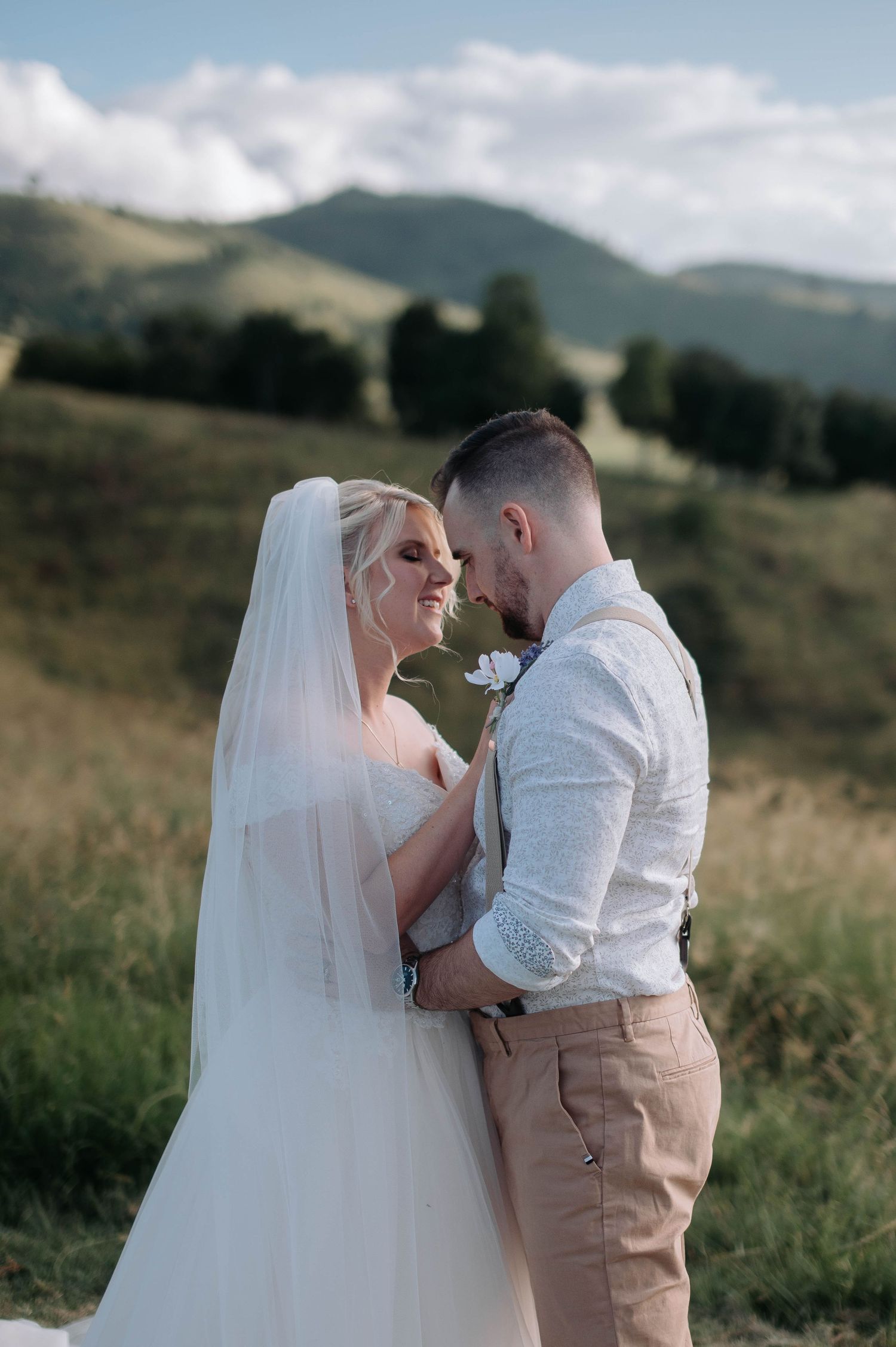 Romantic wedding portrait with couple embracing on hillside.