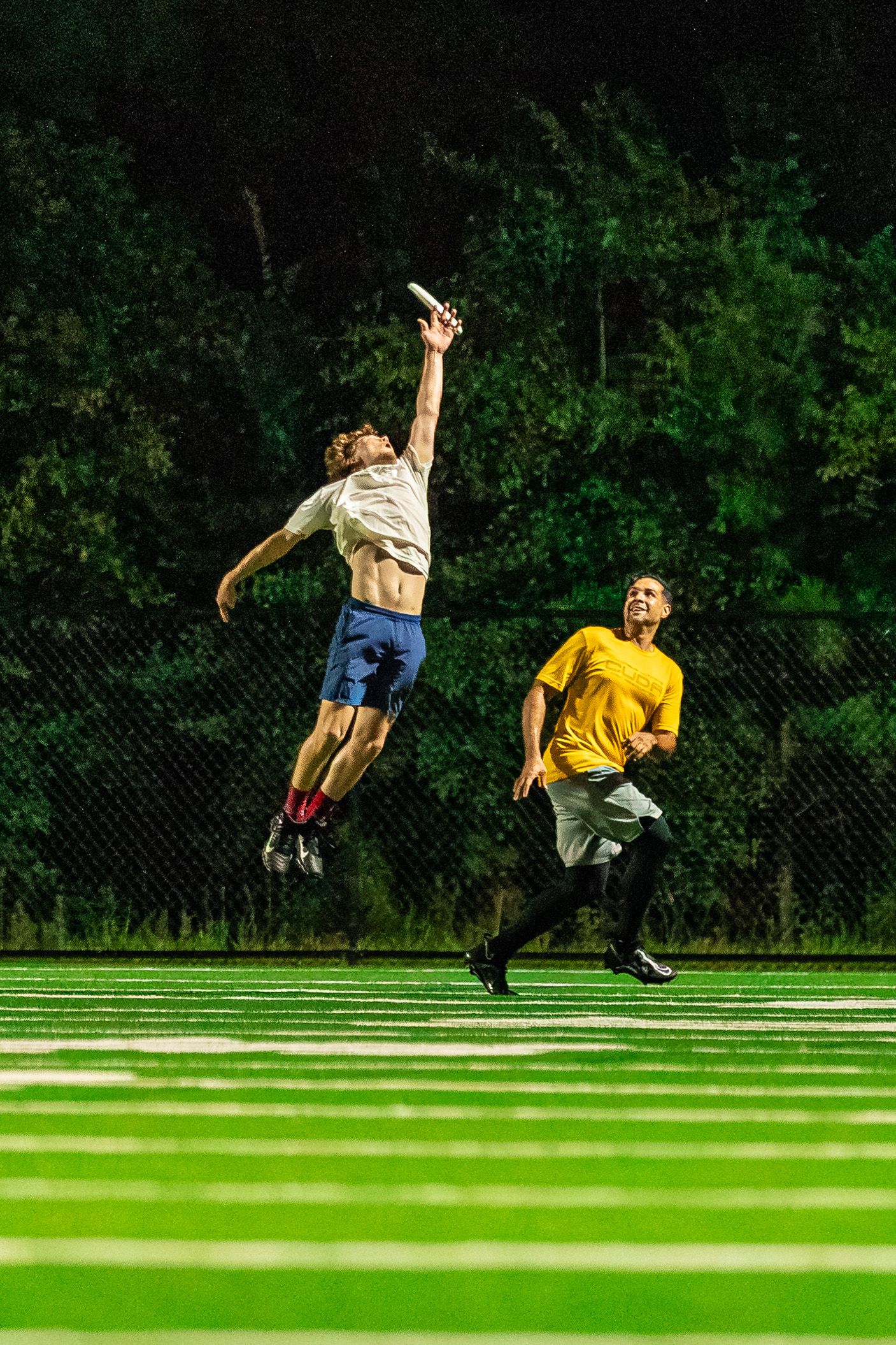 Frisbee player performs a sequence of athletic moves on a turf field against a black background.