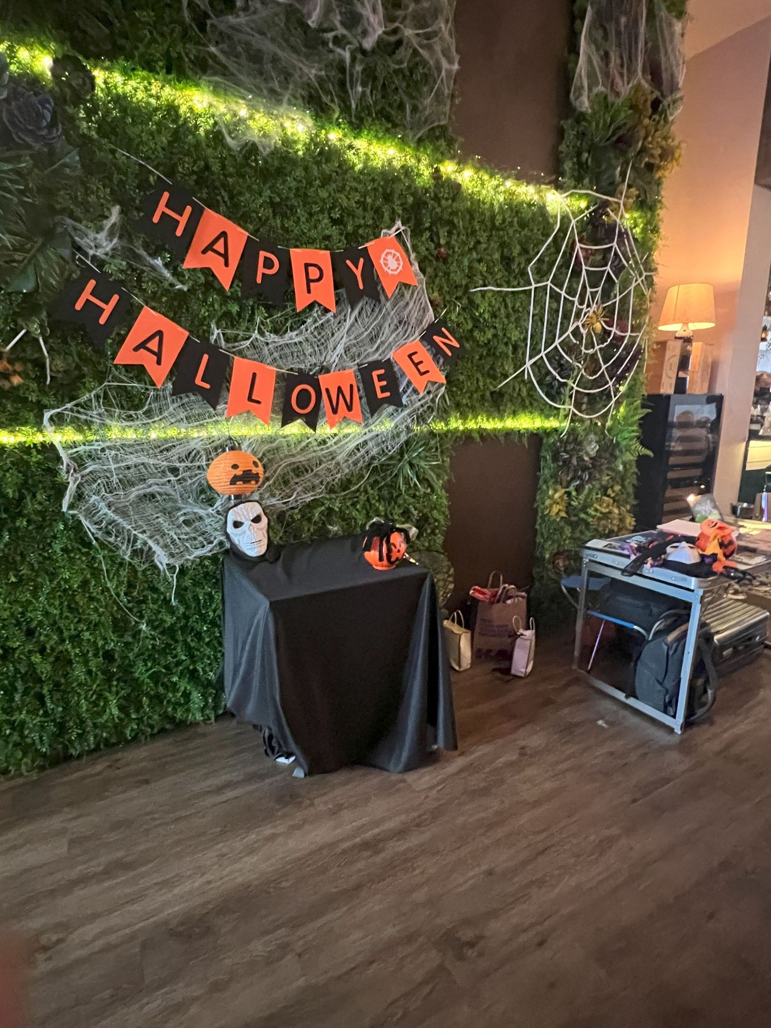 Halloween decorations with Happy Halloween banner, spooky spider webs, and decorative elements on a green hedge wall.