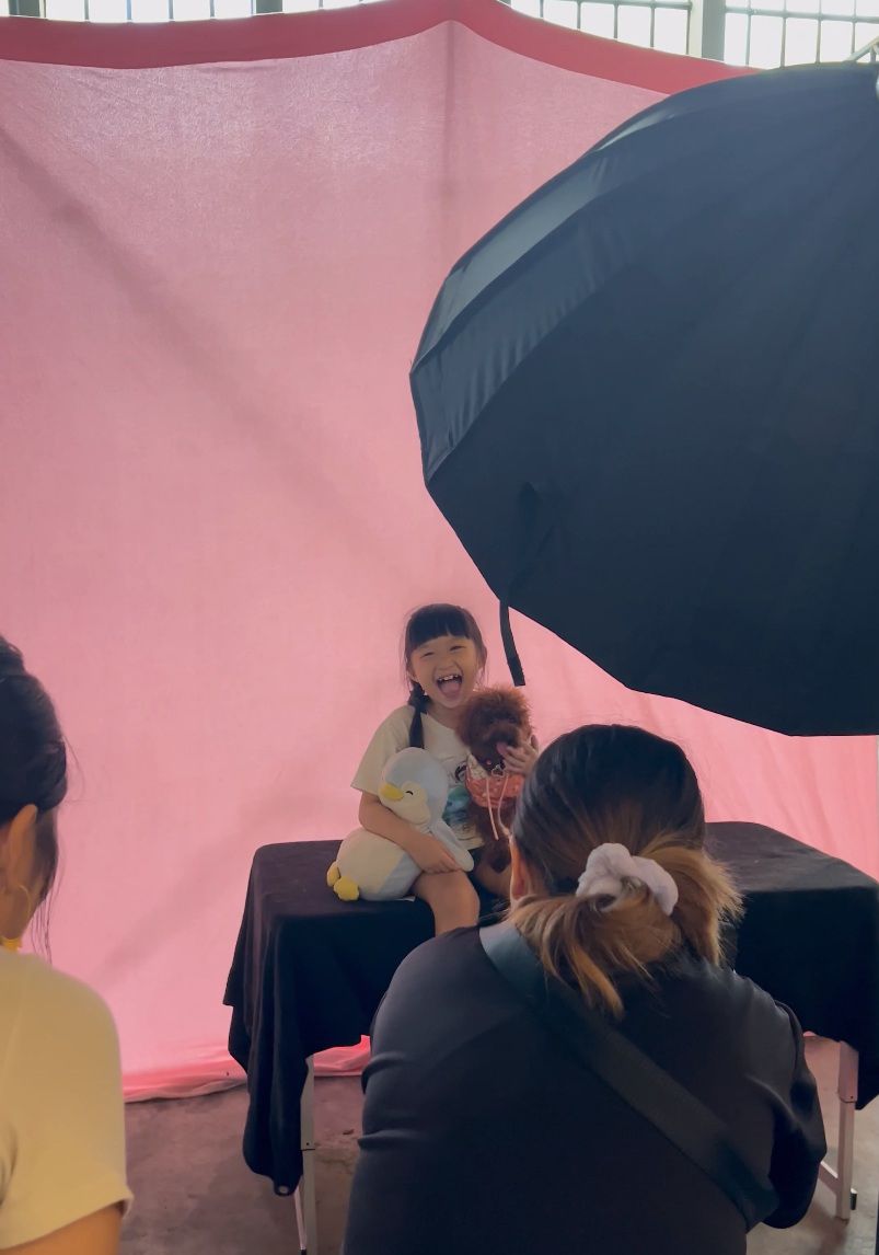 Photography session setup with black umbrella and pink backdrop in a studio setting.