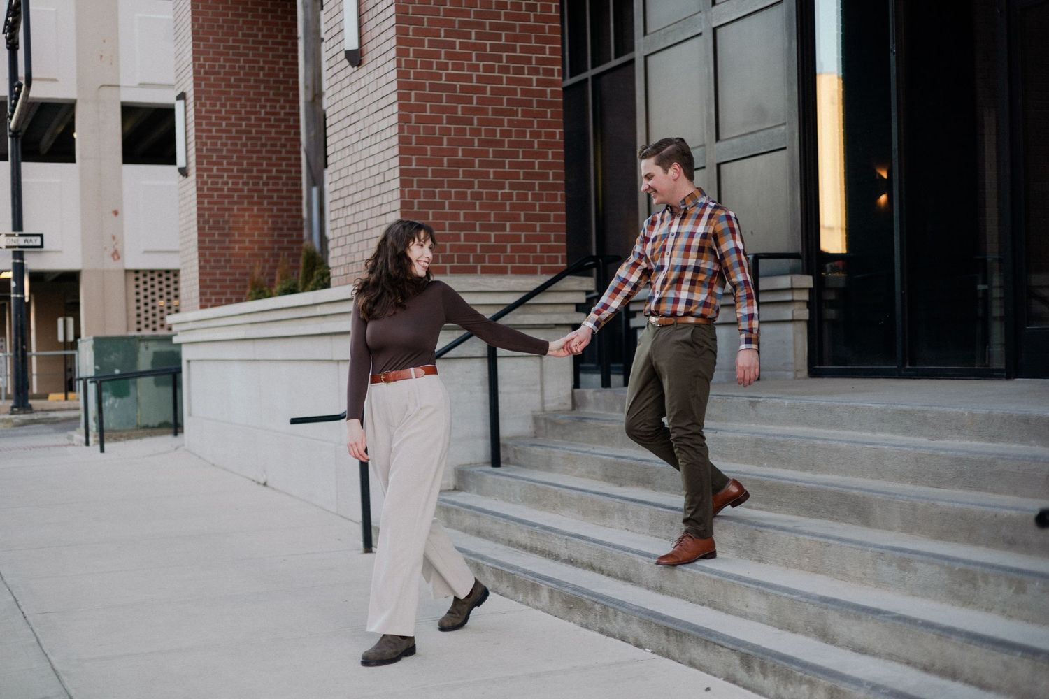 downtown springfield missouri engagement sessions by hotel vandivort, couple walking down the stairs laughing and smiling