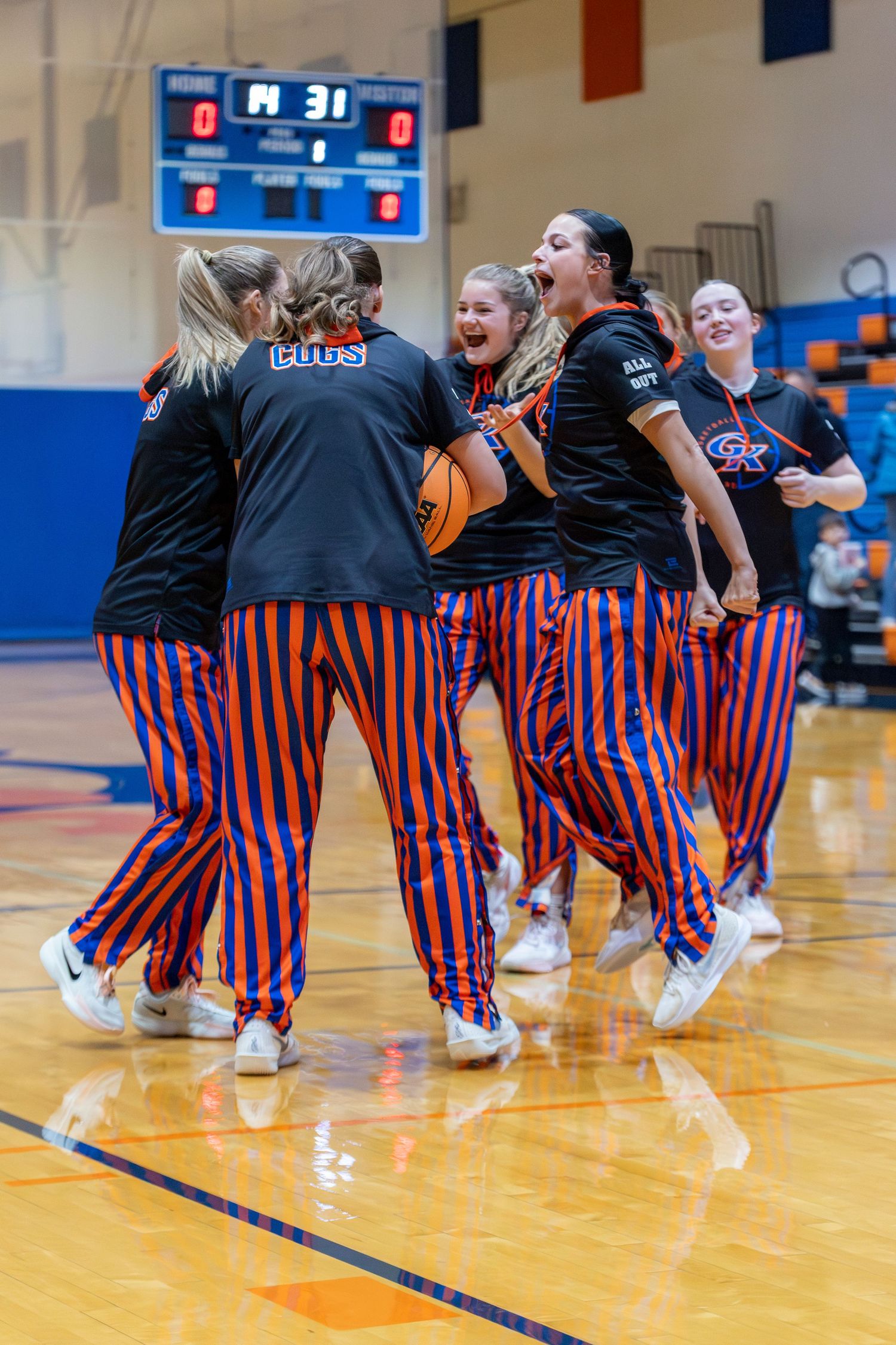 Basketball team members stand in formation on court during pre-game presentation.