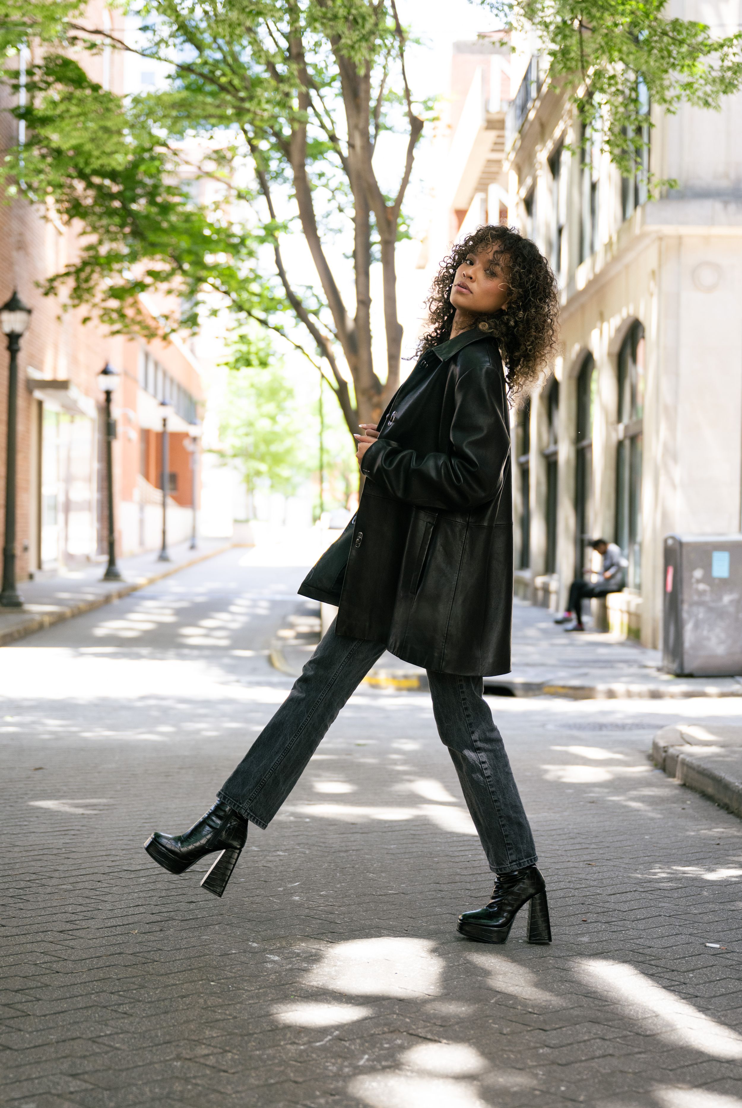 A street fashion shot featuring a black coat, platform boots and casual styling on a charming city sidewalk.