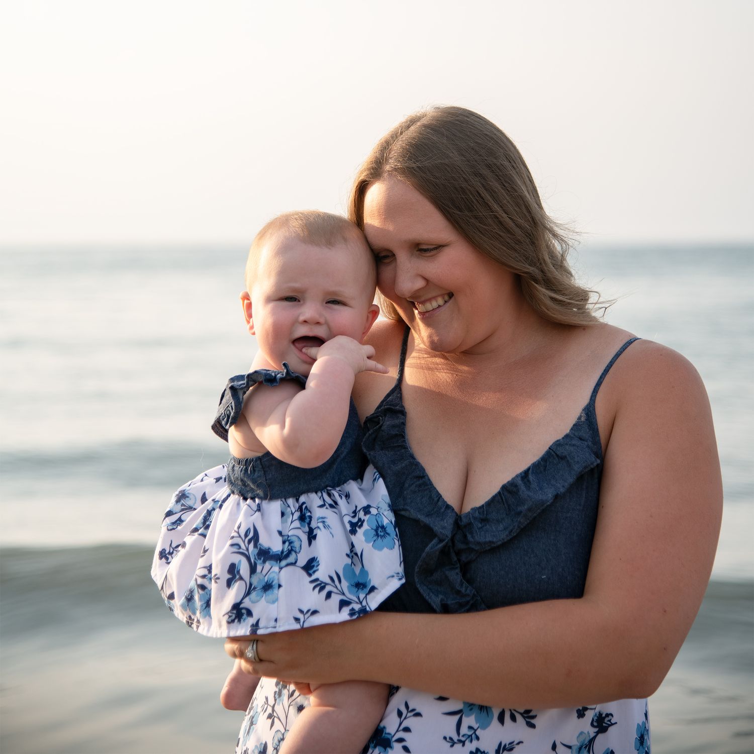 A tender moment between mom and baby is captured at the beach during sunset.