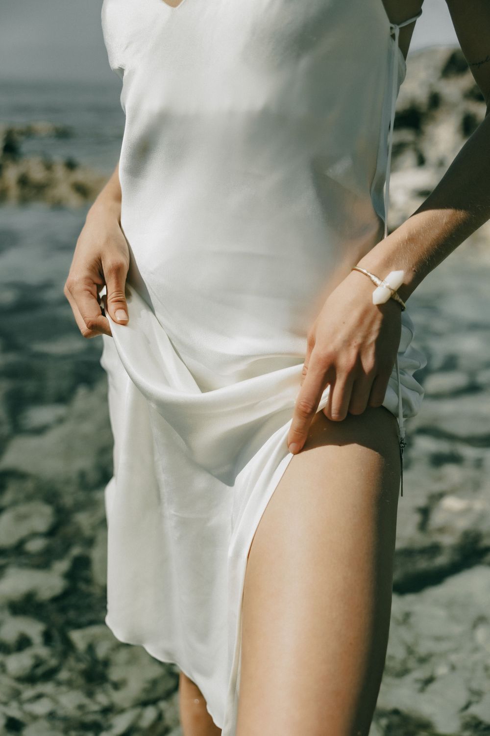 Artistic close-up of white flowing fabric against a beach setting.