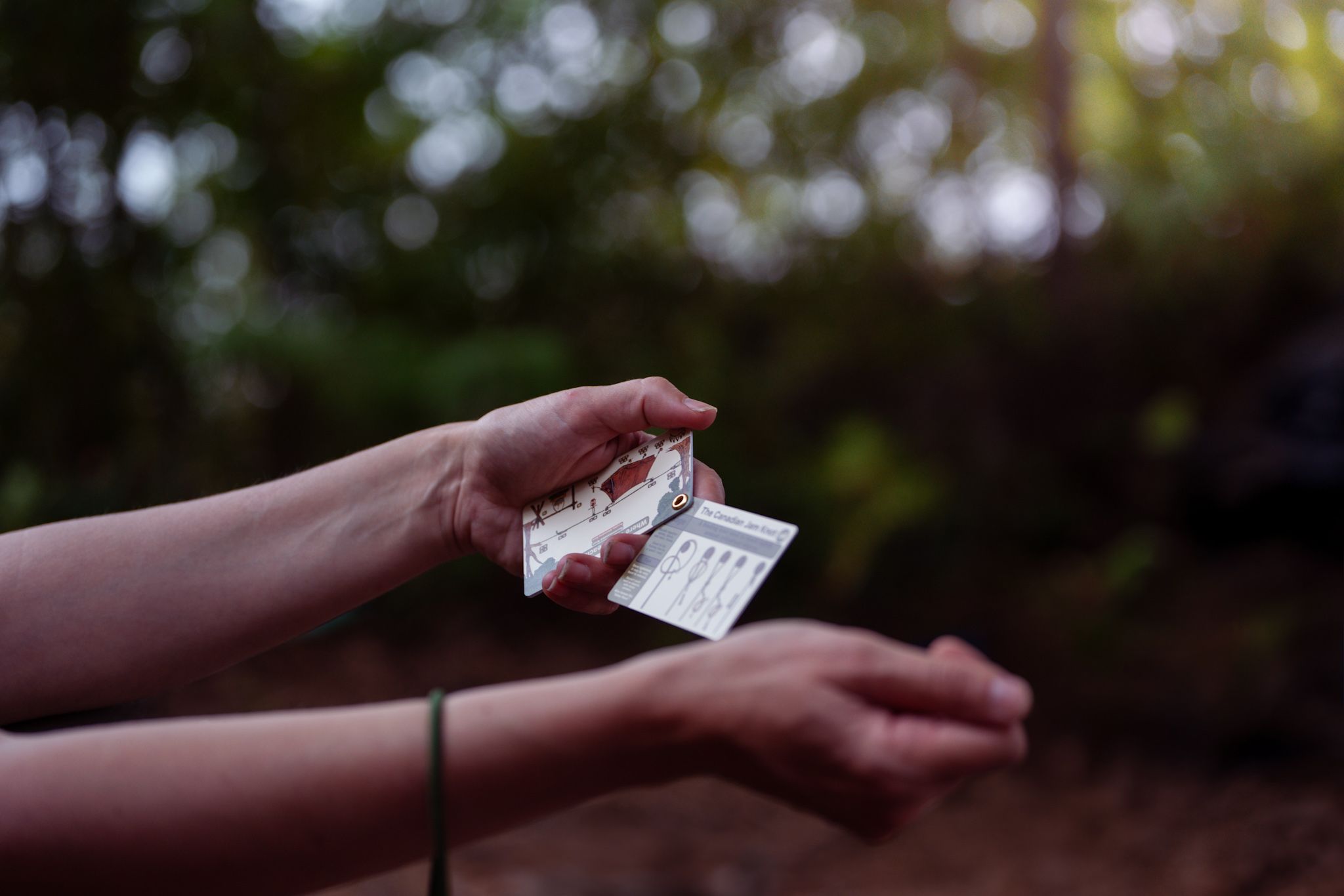 Hands holding a partially unwrapped chocolate bar outdoors during twilight.