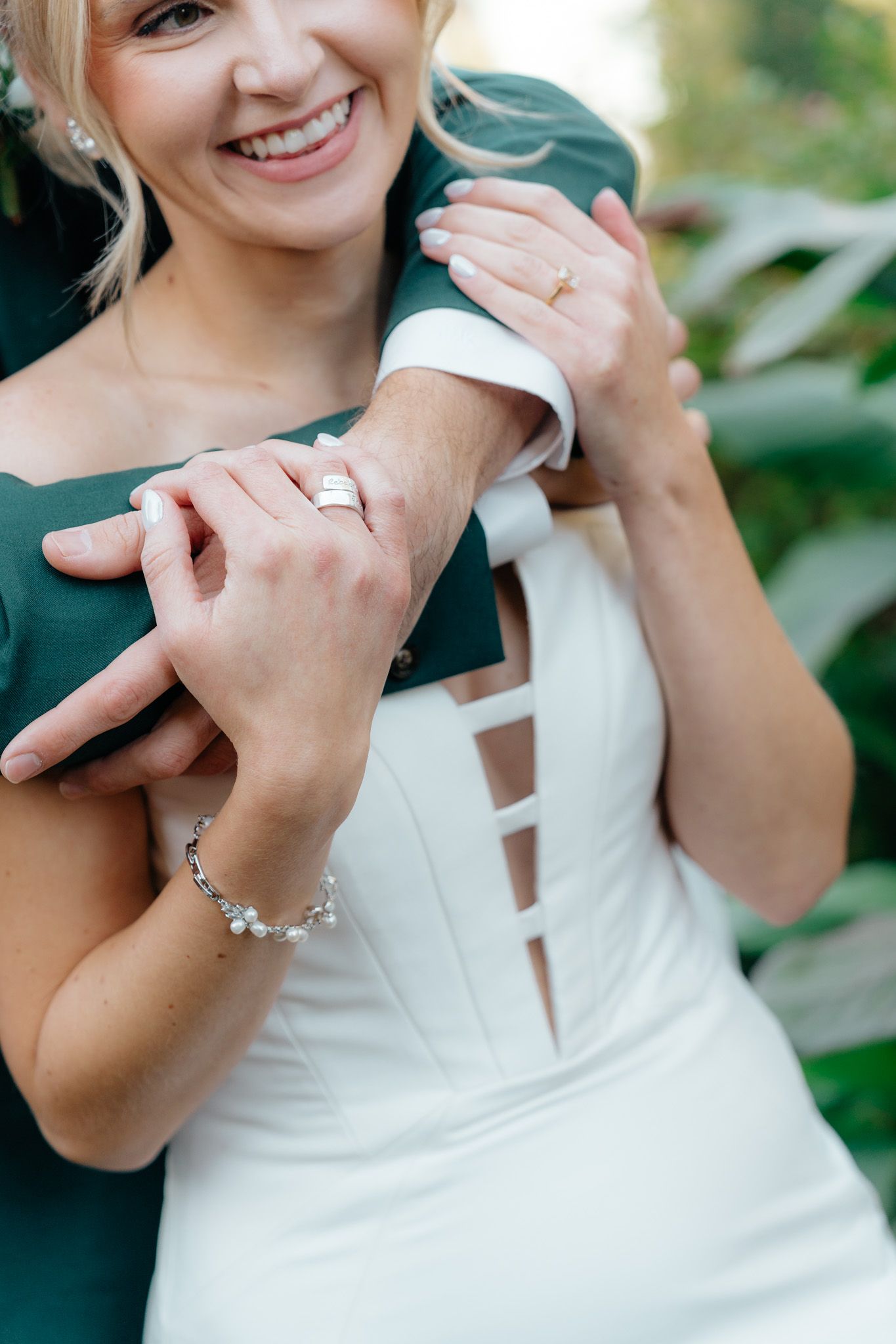 Close-up of hands wearing white dress and delicate bracelet jewelry in elegant wedding photography moment.