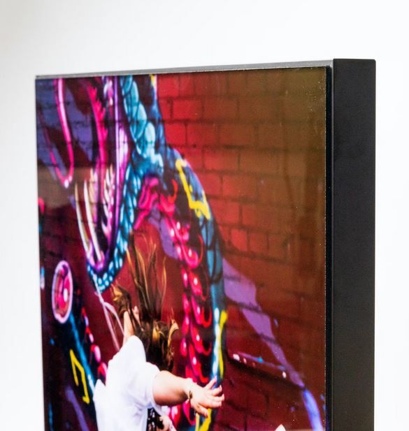 Vibrant street art mural with neon colors and dynamic patterns against a red brick wall in an edge view framed image.