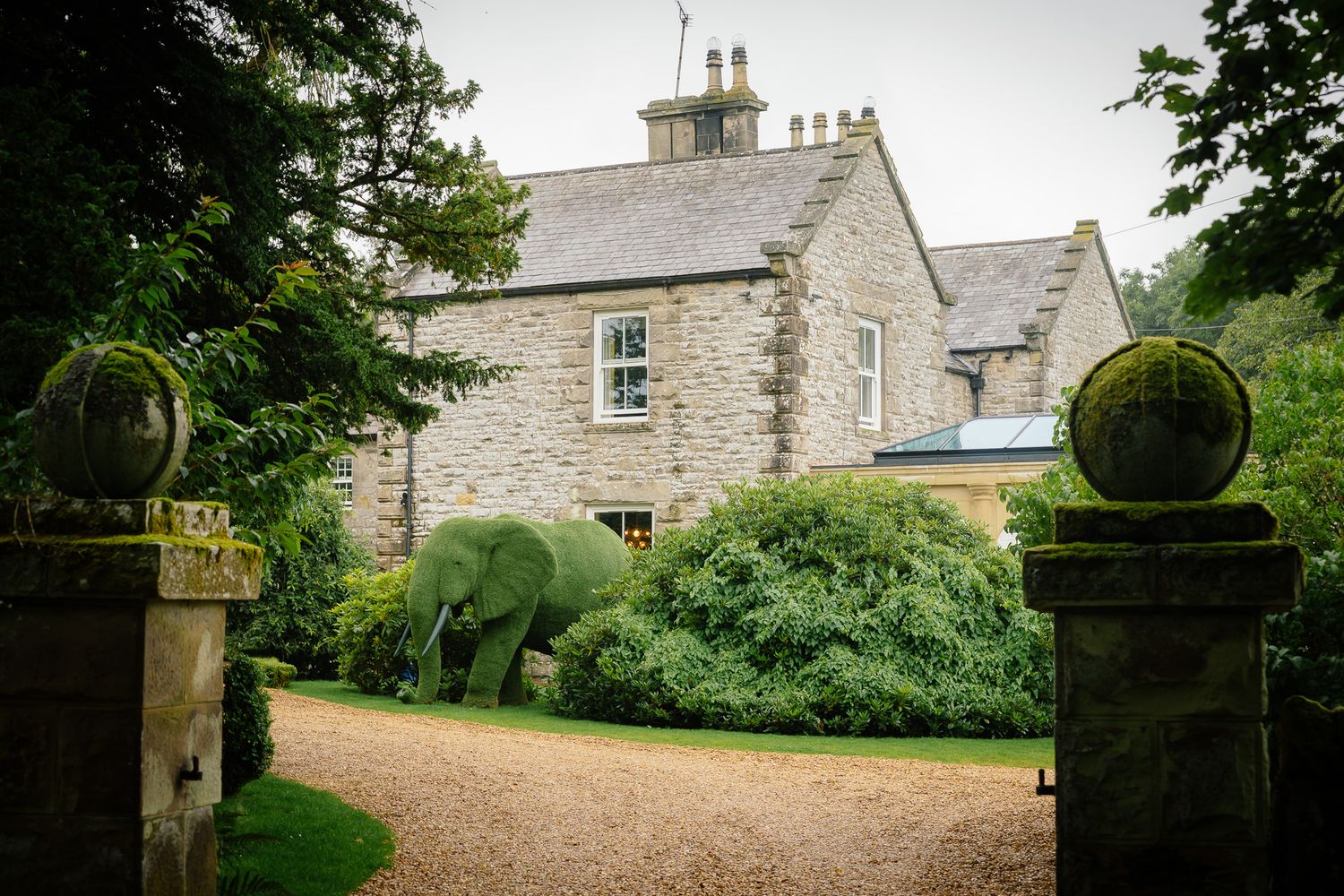 Stone country house exterior with traditional architecture and manicured gardens. Woodhill Hall.