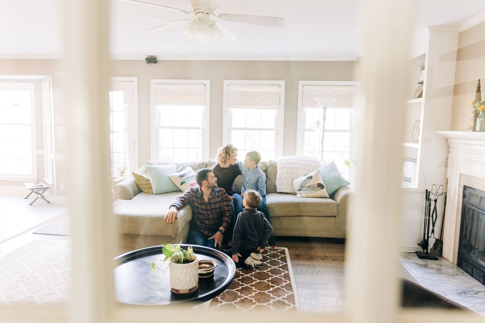 Modern coastal living room features white shiplap walls, ceiling fan, and comfortable neutral seating with ocean views.