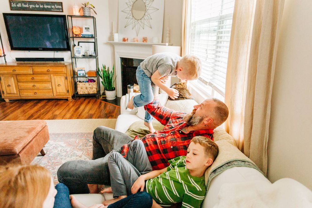 A photo showing a family spending time together at home, with dad holding son up for Charlotte family photos.