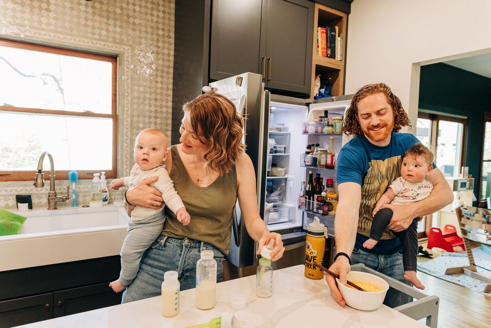 A  family moment in a kitchen showing cooking, eating and interacting together at home with twin babies.