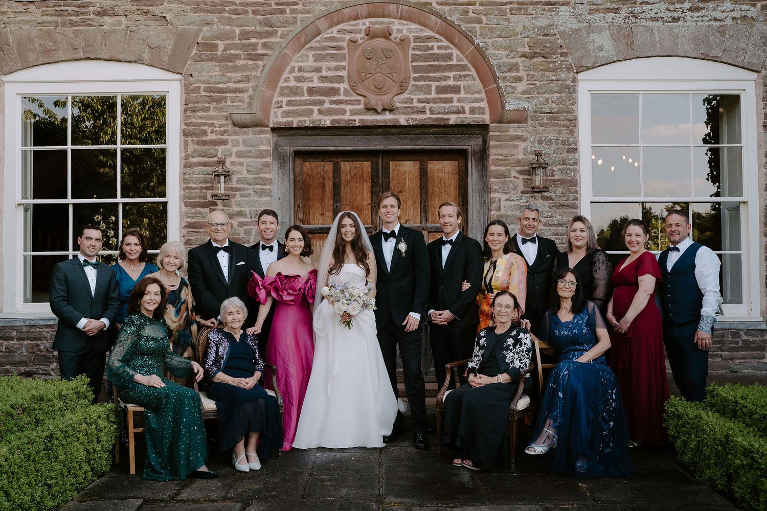 bride and groom portrait with family outside dewsall court in herefordshire