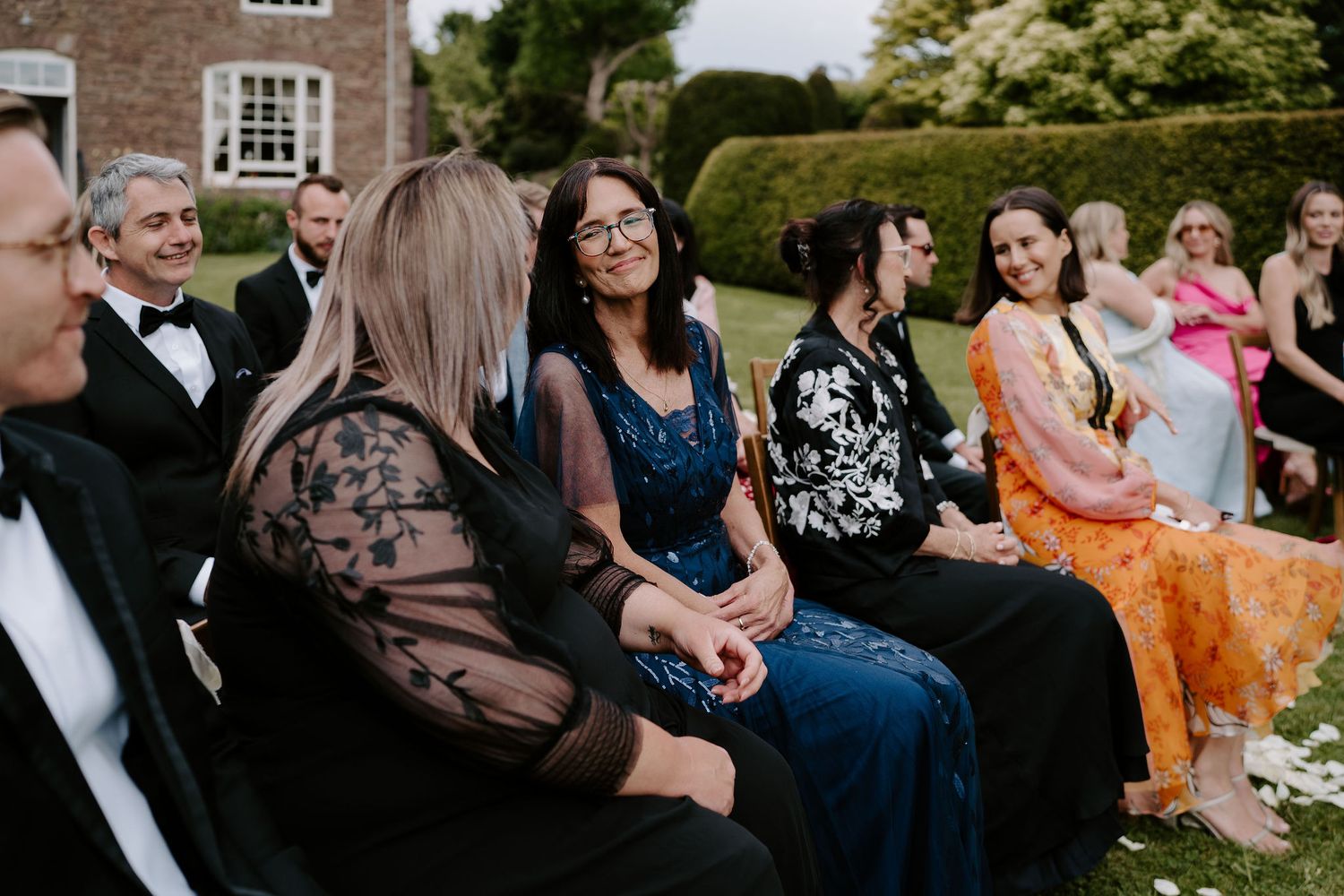 grooms mother smiling at the grooms sister while waiting for the brides entrance to the ceremony at dewsall court in herefordshire