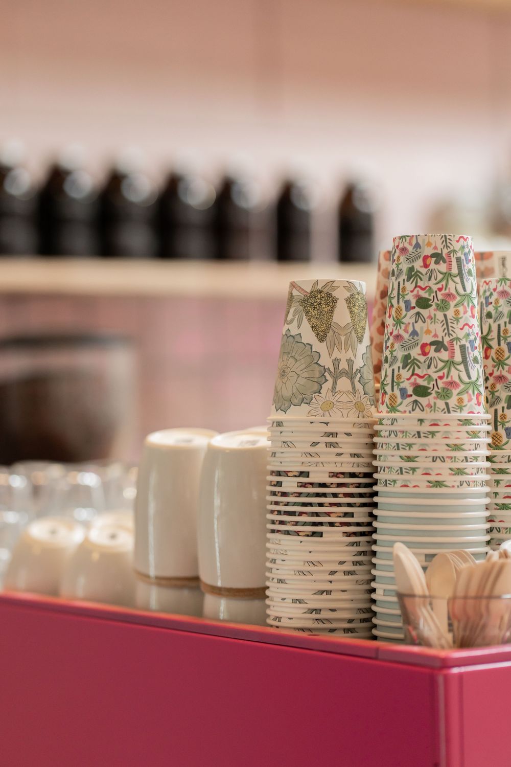 Decorative floral patterned paper cups arranged in a row on a red surface with soft focus.