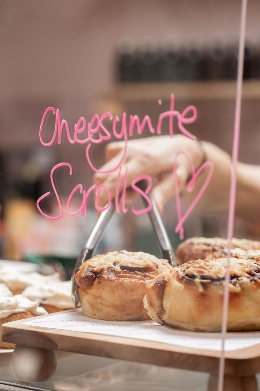 Fresh baked pastries displayed on white serving platters with pink neon signage.