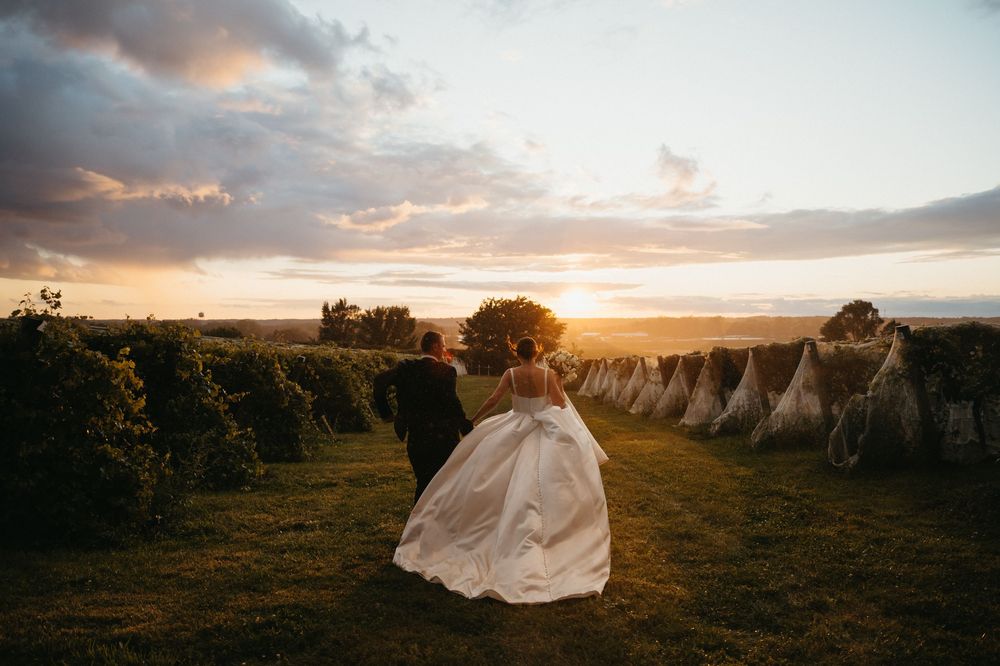 A stunning sunset wedding portrait session in a golden field with flowing white dress and dramatic sky.