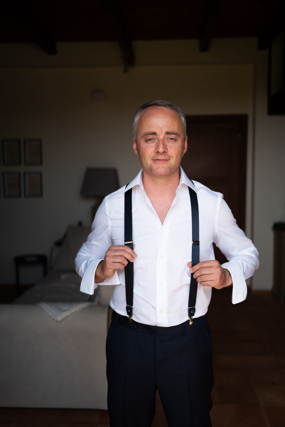 Man in white dress shirt and black suspenders adjusts his outfit in a series of progressive shots.