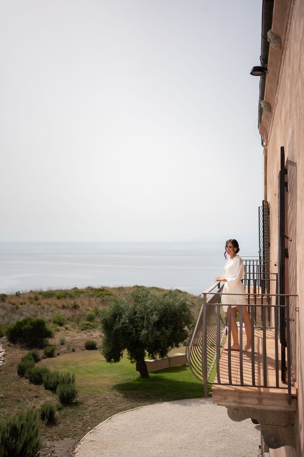 Scenic view of a Mediterranean balcony overlooking olive groves and distant coastline.
