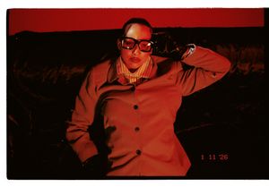 A series of red-tinted photographs showing someone posing in a dark setting with dramatic lighting effects.