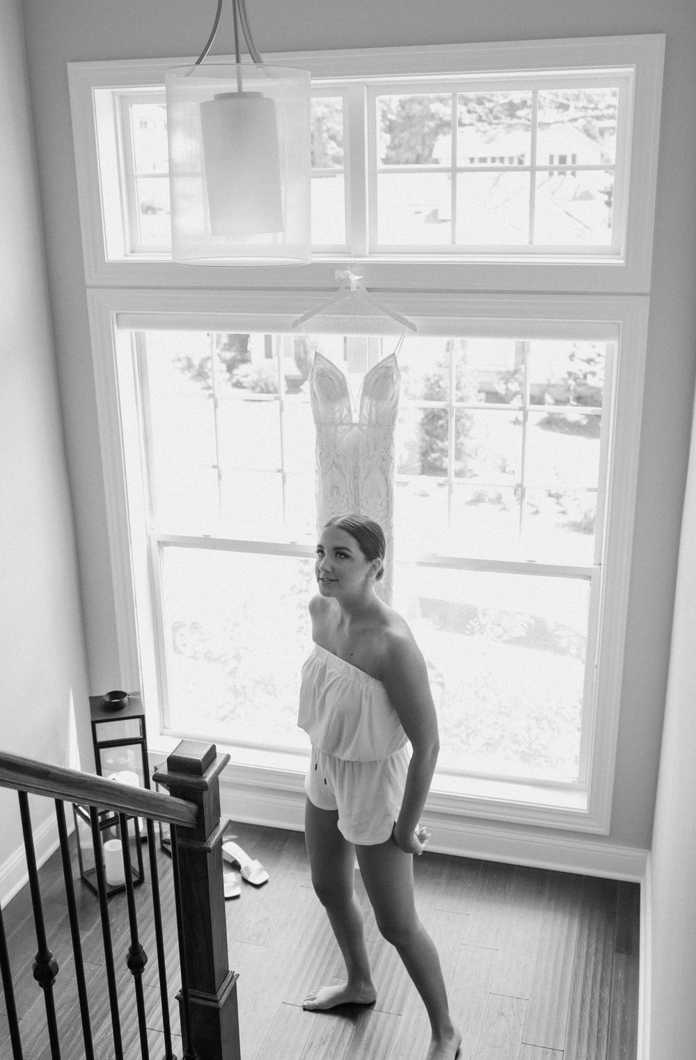 Black and white photo of someone getting ready by a bright window.