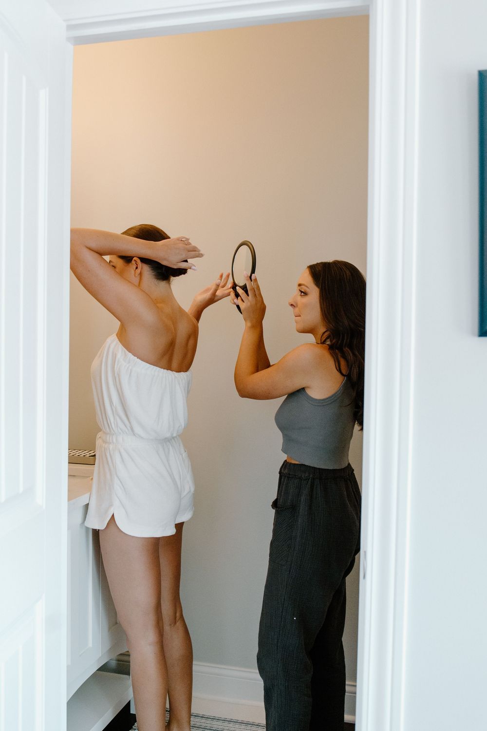 Two people in casual attire dance together in a bright white interior space.