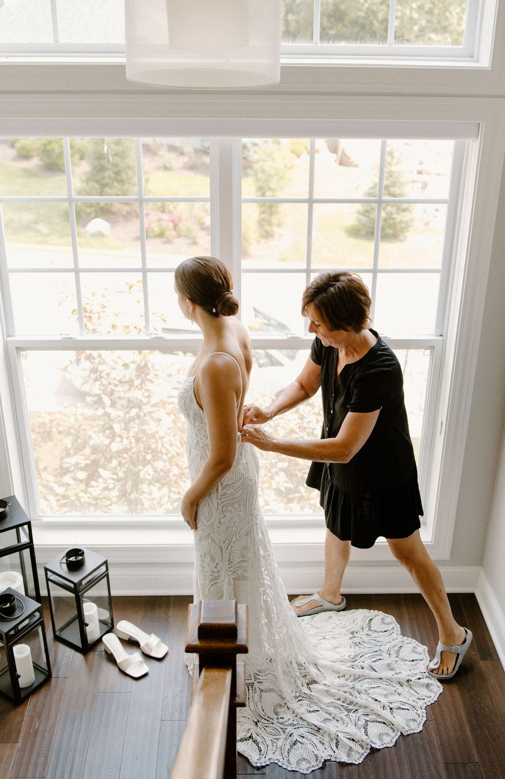 A wedding dress being fitted and adjusted in a bright sunlit room.