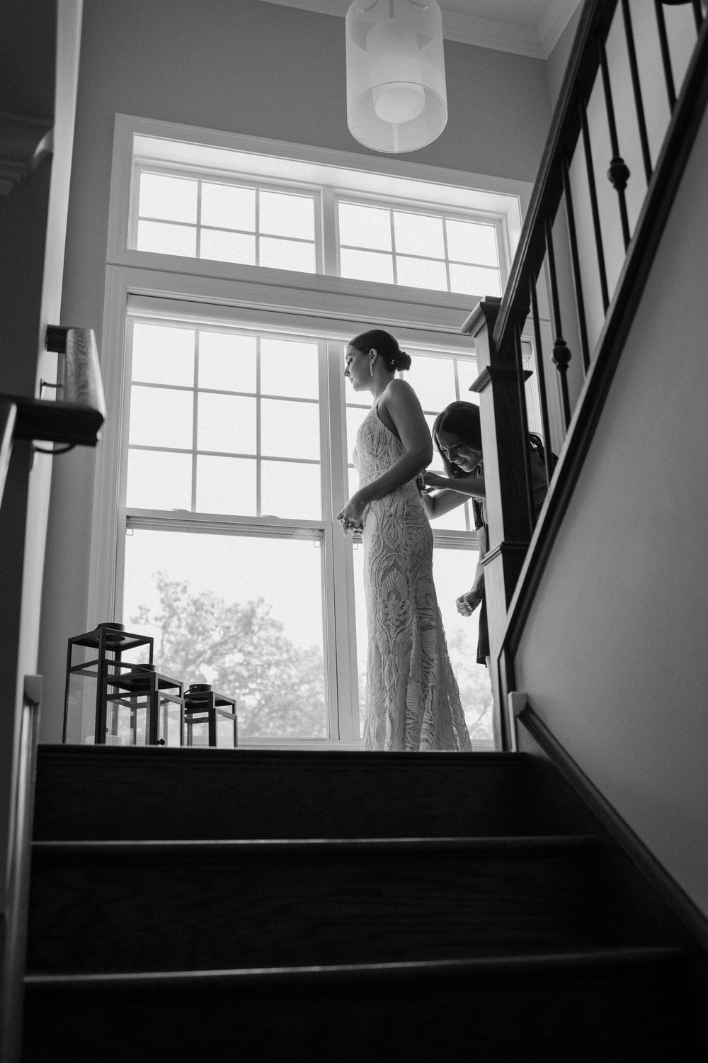 Black and white series captures wedding dress silhouettes against bright windows on a staircase.
