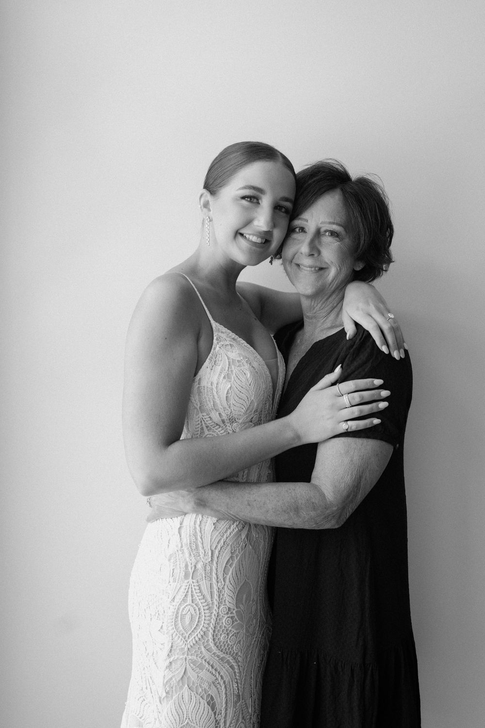 Two people share an intimate black and white portrait moment in formal attire.