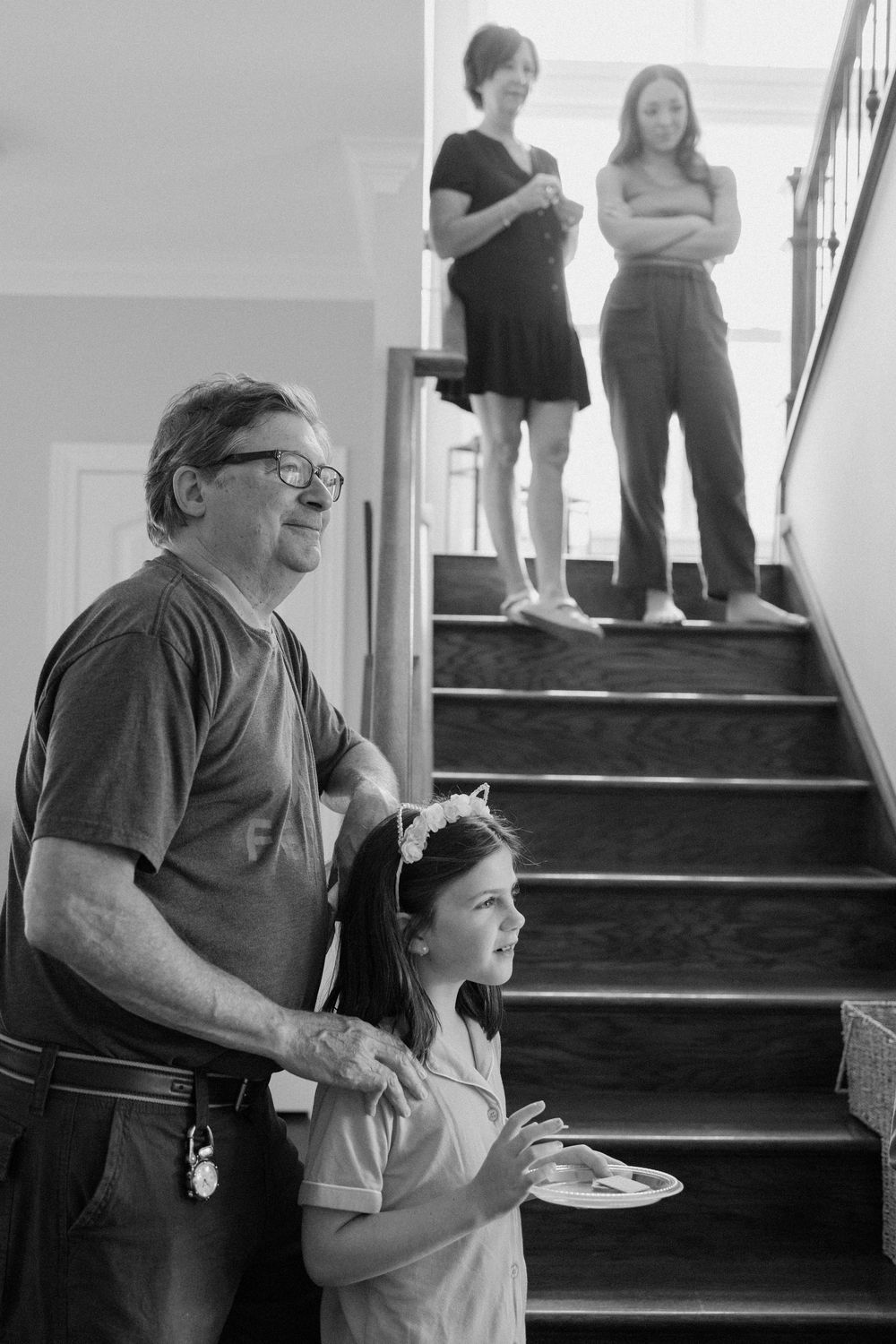 Black and white photo of people gathered on stairs during casual indoor event.