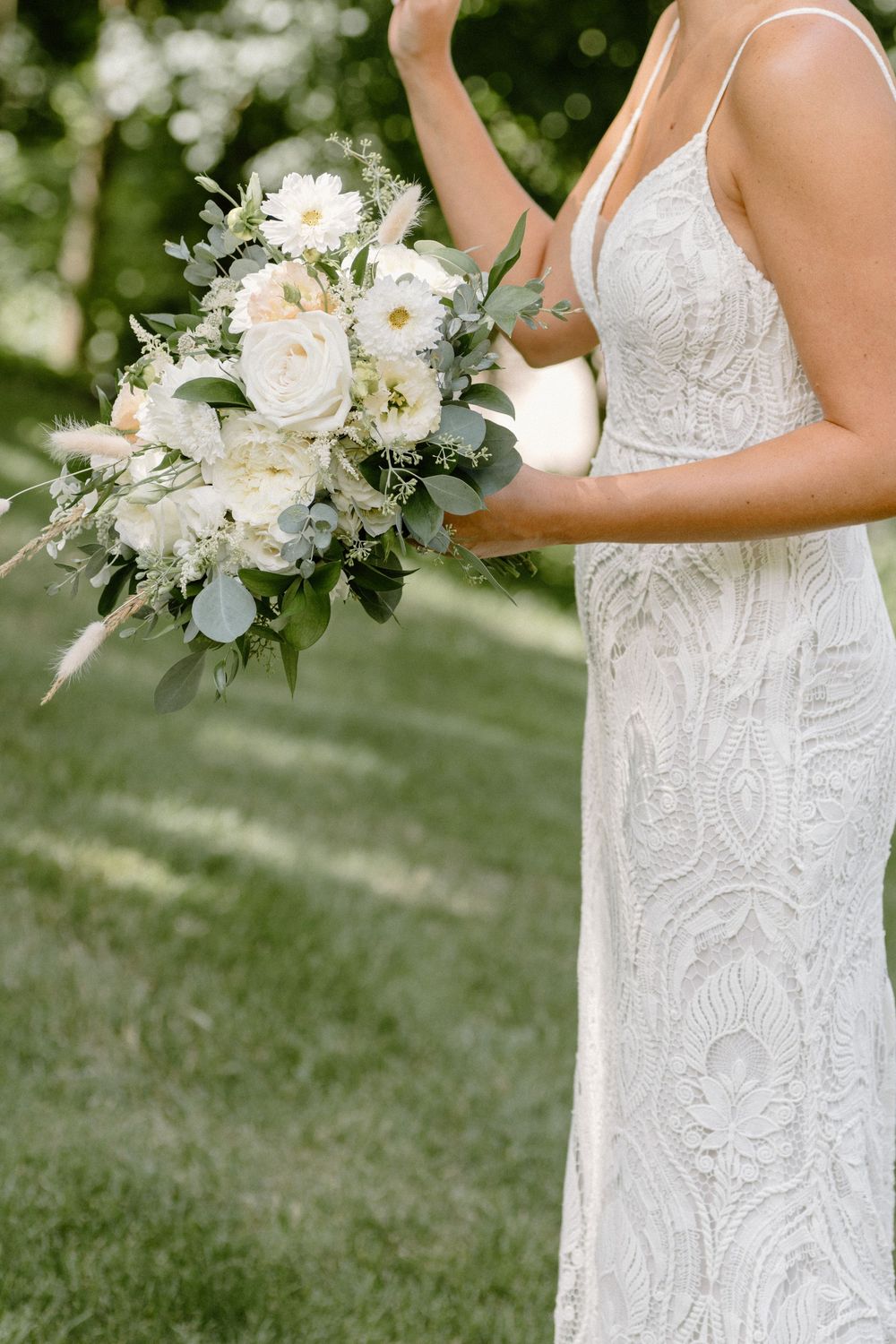 White bridal bouquets with roses and greenery shown in detail against a garden backdrop.