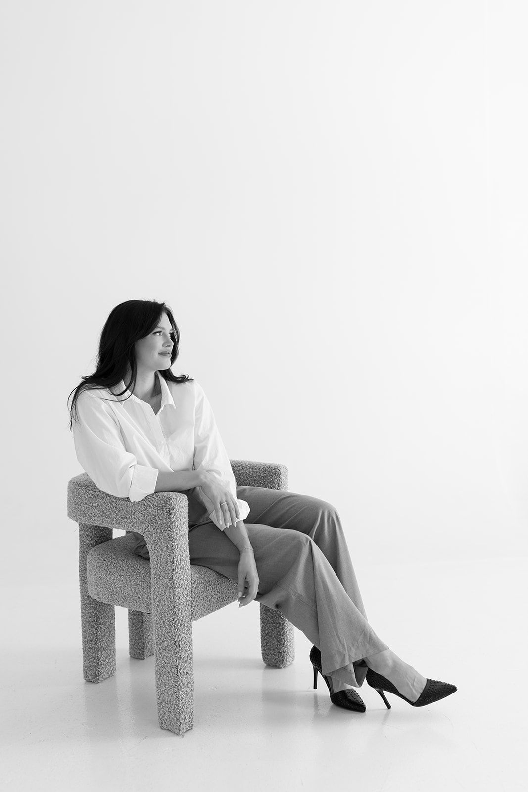 Black and white photo series of someone sitting in different positions on a textured geometric chair against white backdrop.