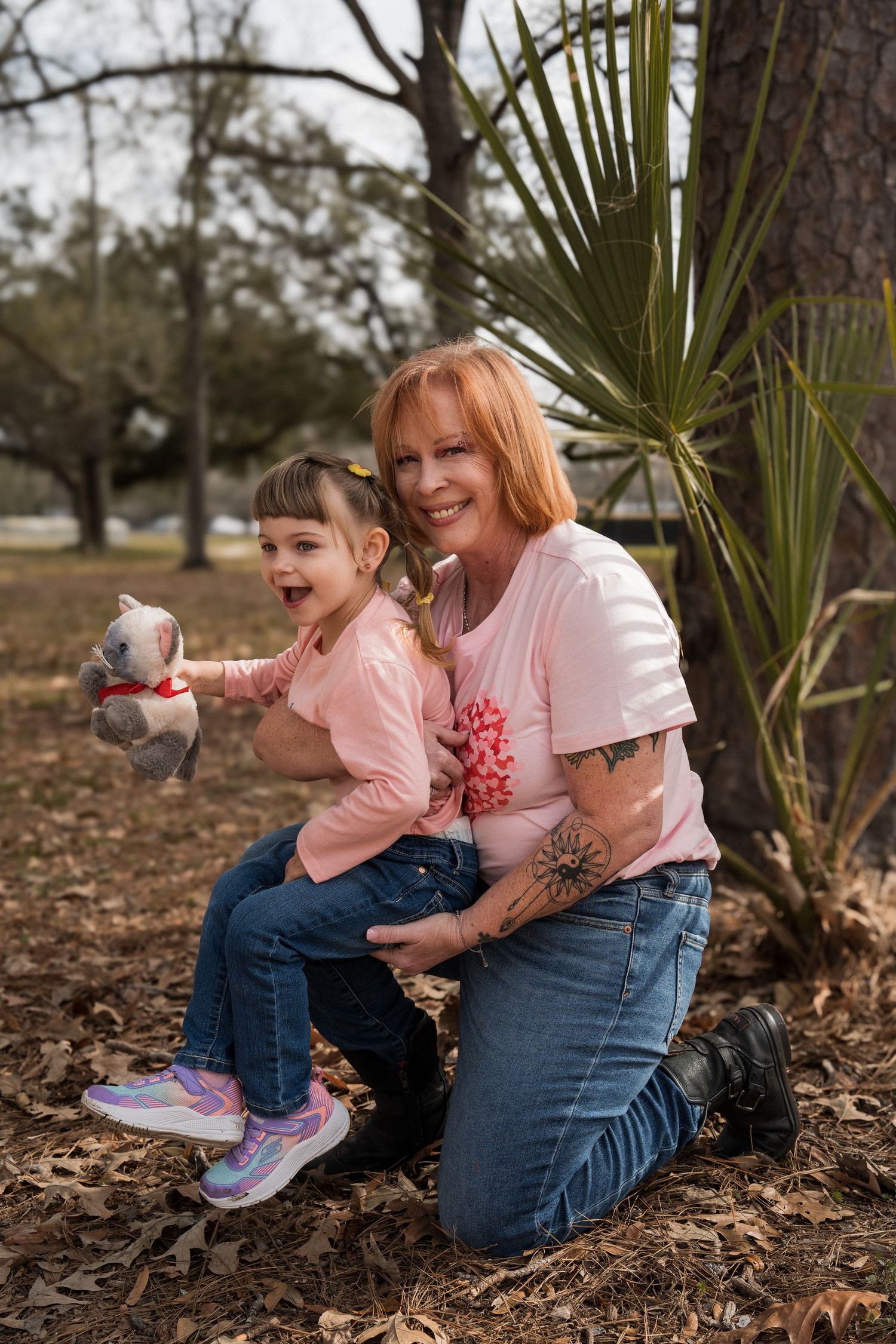 A tender moment shared between family members sitting among fallen leaves and palm fronds.
