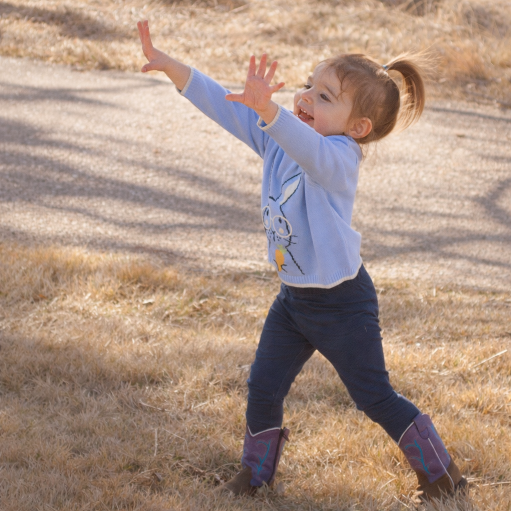 child standing happy reaching for bubbles
