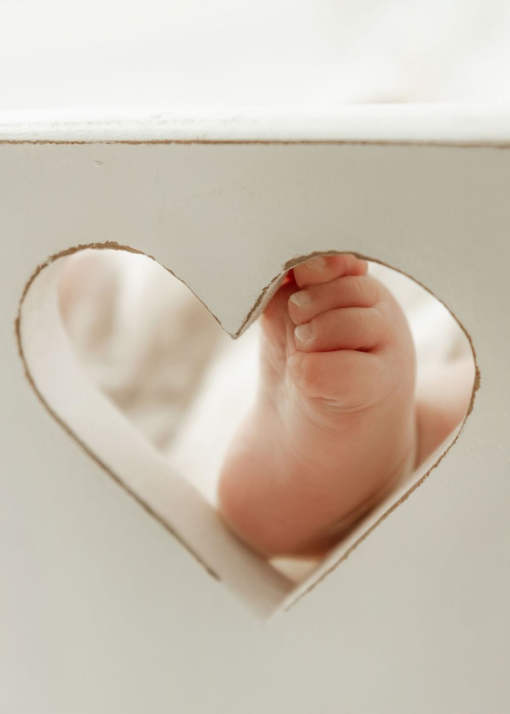 A series of heart-shaped cutouts in white paper revealing a soft pink background beneath each one.