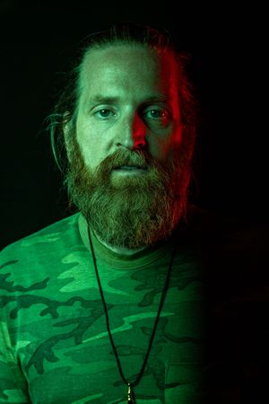 Portrait with dramatic green lighting and camouflage pattern clothing. photography st louis.