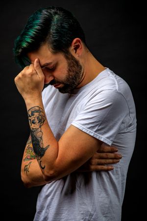 Person in white t-shirt showing emotional distress with visible arm tattoo. photography st louis.