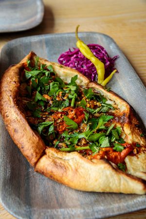 Flatbread topped with meat, fresh herbs, and purple cabbage served on gray plates. photography st louis.