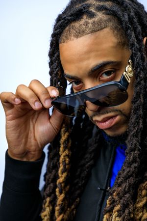 Portrait series showing person with dreadlocks and sunglasses making playful expressions against dark background. photography st louis.