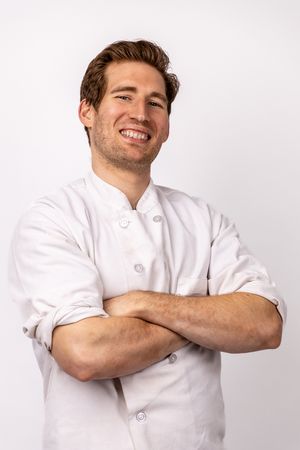 Professional headshots in white chef's coat showing confident crossed arms pose. portrait photography st louis.