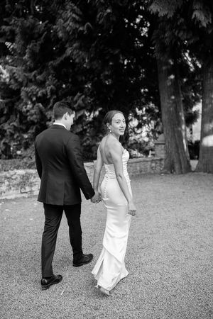 A playful sequence of a couple in wedding attire bending down to pick something up from a grassy lawn  at Birtsmorten Court