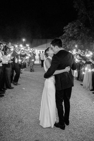 A couple in formal attire dances together while holding sparklers at a nighttime outdoor wedding reception  at Birtsmorten Court